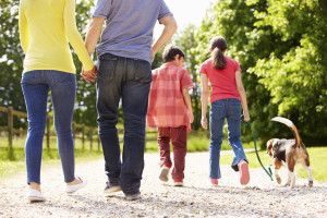 Rear View Of Family Taking Dog For Walk In Countryside