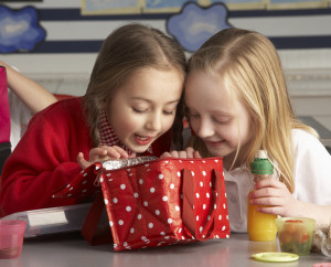 Primary School Pupils Enjoying Packed Lunch In Classroom