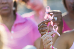 Cropped group of multi-ethnic teenage girls and young women holding breast cancer awareness ribbons in their hands, and wearing pink shirts.