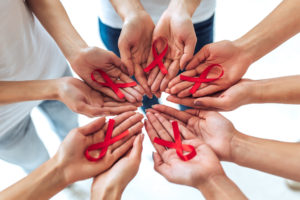 Group of young multiracial woman with red ribbons in hands are struggling against HIV/AIDS. AIDS awareness concept.